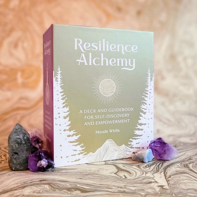 Photo of "Resilience Alchemy" standing against a gold marble backdrop next to several crystals