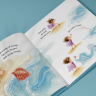 Open picture book showing watercolor illustration of child playing on a beach